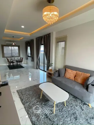Modern living room with elegant decor and open dining area, featuring plush sofa and stylish lighting.