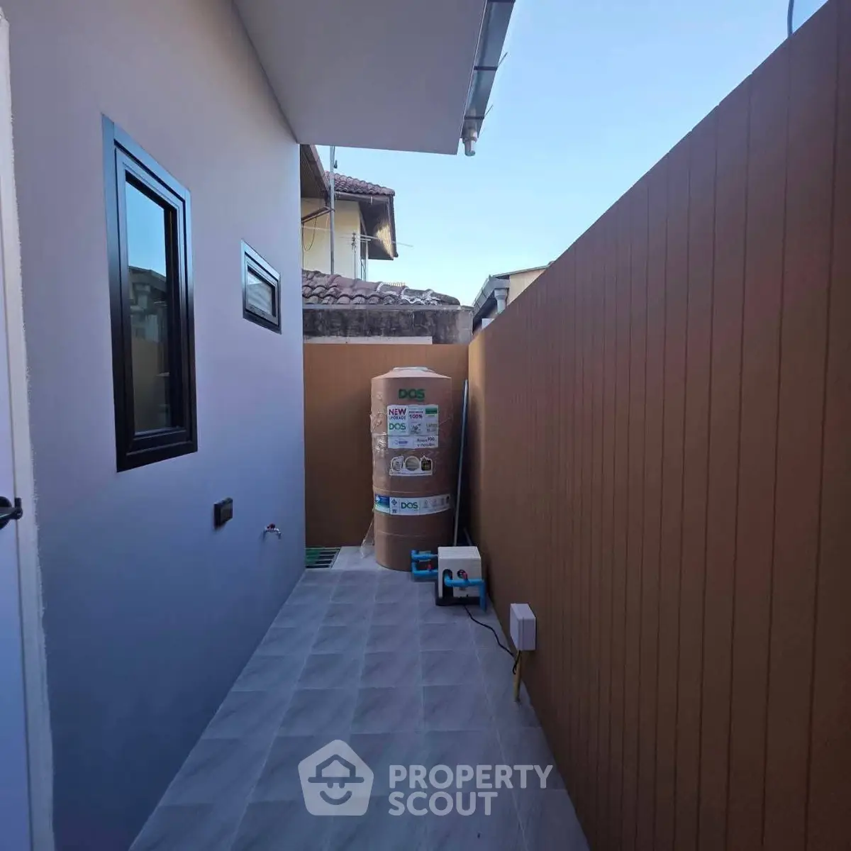 Modern outdoor utility area with water heater and sleek fencing in a residential property.