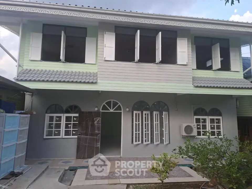 Charming two-story house with unique architectural design and lush garden, perfect for family living.