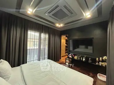Luxurious bedroom with modern decor and large TV, featuring elegant lighting and plush bedding.