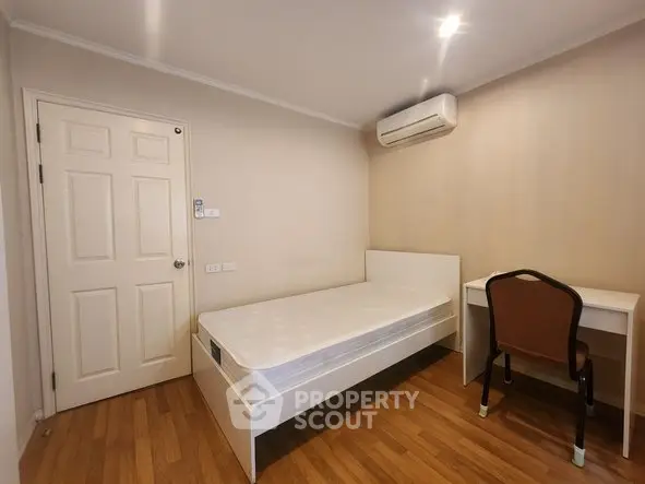 Cozy bedroom with single bed, desk, and air conditioning in modern apartment.