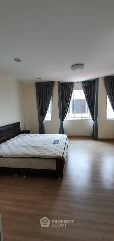 Spacious bedroom with large windows and elegant curtains in modern apartment