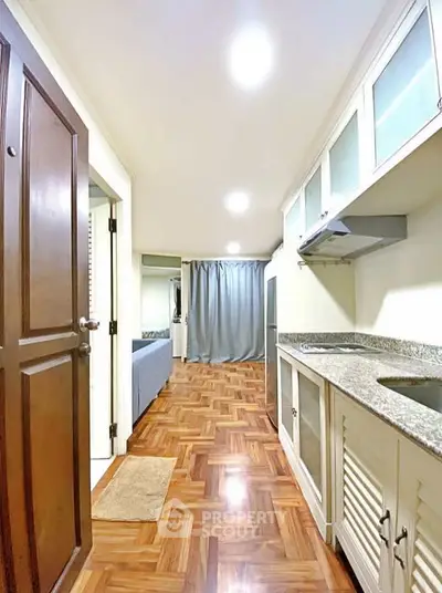 Spacious kitchen with granite countertops and wooden flooring in modern apartment