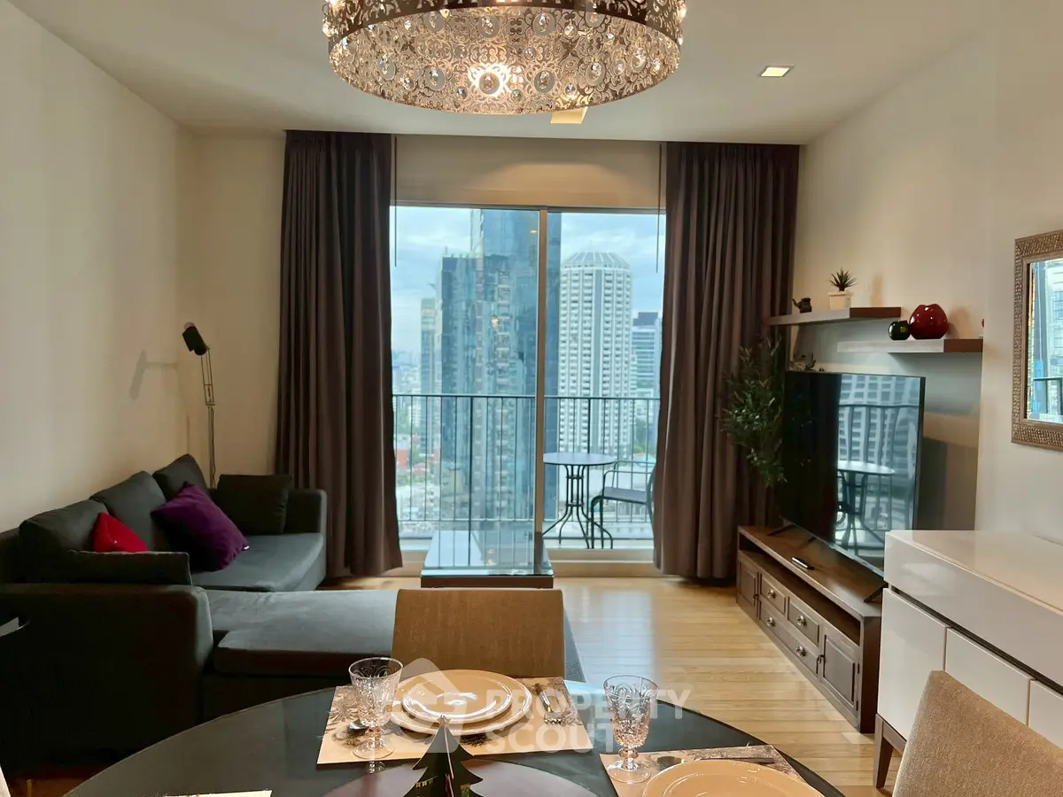 Modern living room with city view, elegant chandelier, and stylish decor in a high-rise apartment.
