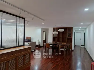 Spacious open-plan living and dining area with modern furnishings and wooden flooring.