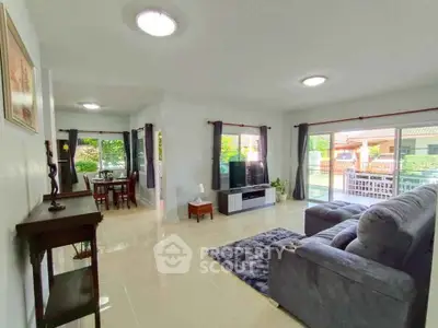 Spacious living room with modern decor and large windows offering natural light and garden view.