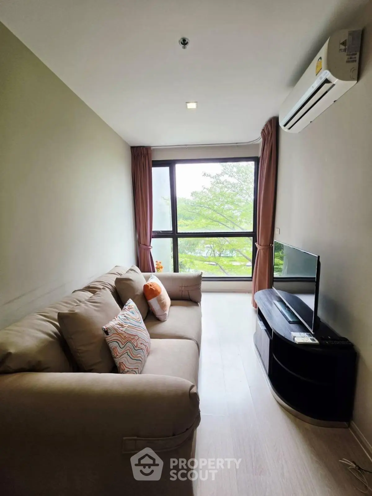 Cozy living room with large window and modern furnishings, perfect for relaxation.