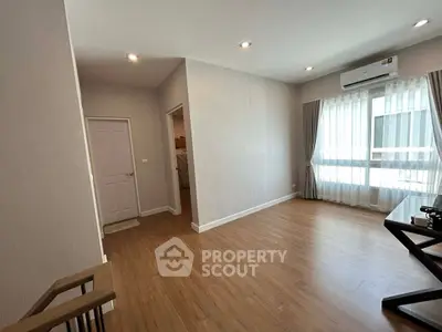 Spacious living room with wooden flooring and large windows in modern apartment