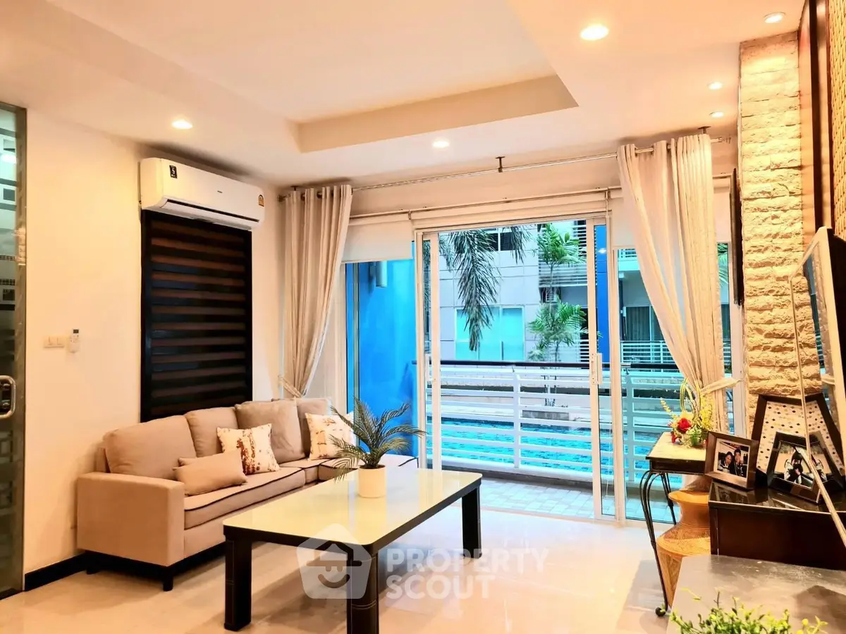 Modern living room with pool view, elegant decor, and ample natural light.