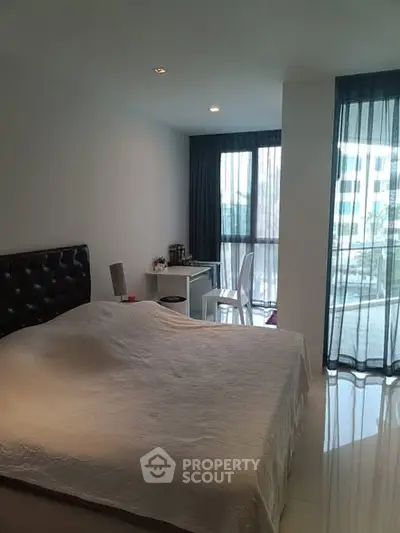 Modern bedroom with large window and balcony access in a stylish apartment.