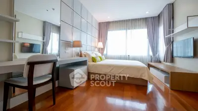 Spacious modern bedroom with wooden flooring and large windows for natural light.
