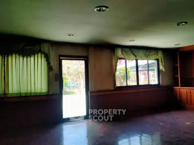 Spacious living room with large windows and elegant curtains, offering ample natural light and garden views.