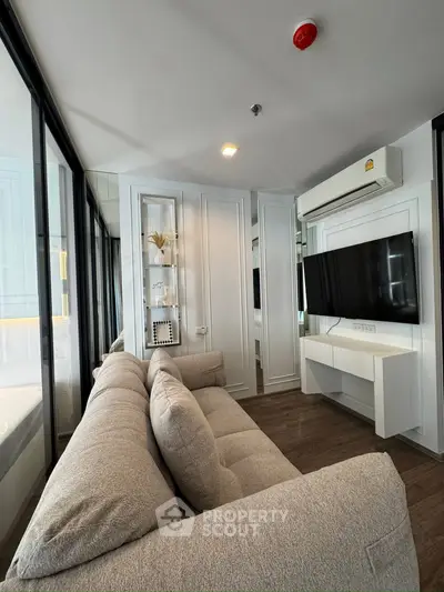 Modern living room with cozy sofa, wall-mounted TV, and elegant decor in a stylish apartment.