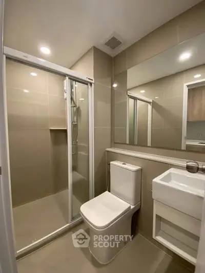 Modern bathroom with sleek design and glass shower enclosure in a contemporary apartment.