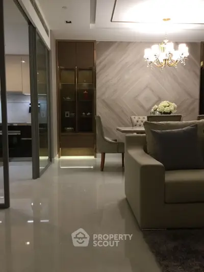 Luxurious modern living room with elegant chandelier and open kitchen layout.