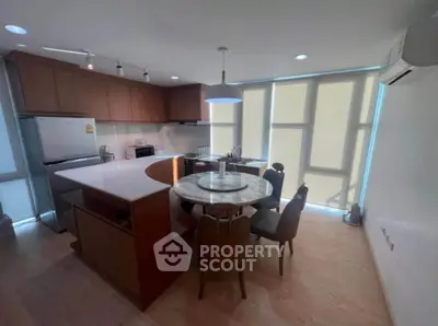 Modern kitchen with open layout and stylish dining area, featuring sleek appliances and natural lighting.