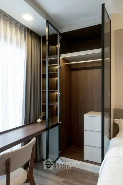 Modern bedroom with sleek glass wardrobe and cozy workspace