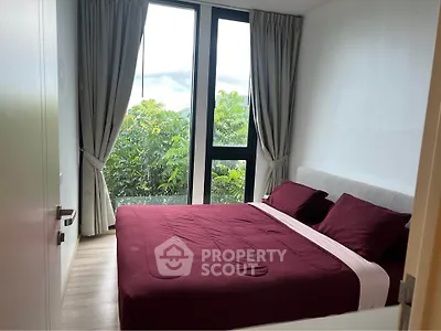 Cozy bedroom with large windows and lush green view, featuring elegant curtains and stylish bedding.