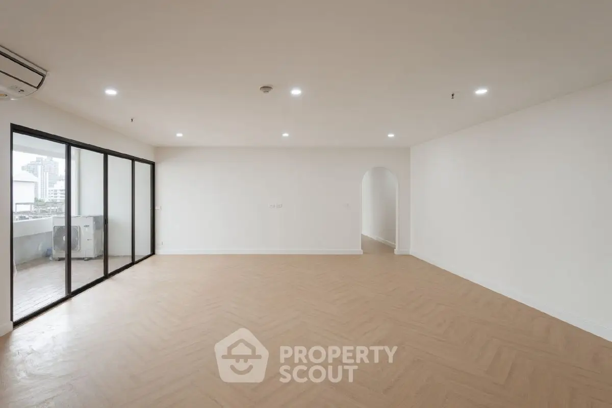 Spacious empty living room with large windows and balcony access