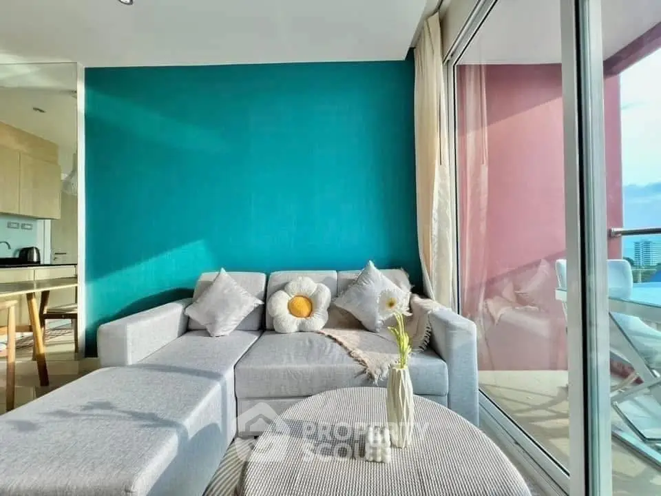 Modern living room with stylish decor and large windows opening to a balcony with city views.