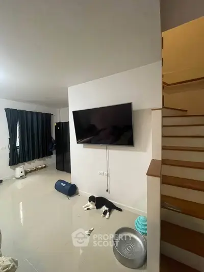 Modern living room with sleek TV and staircase, perfect for cozy family gatherings.