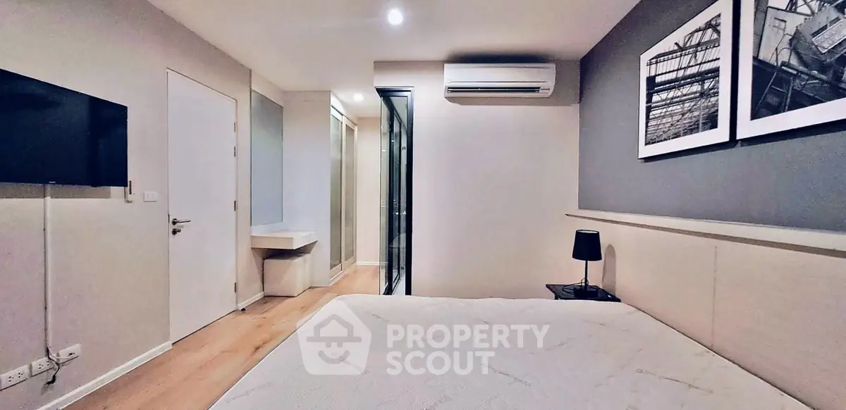 Modern bedroom with sleek design, featuring a wall-mounted TV, air conditioning, and stylish decor.