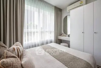 Cozy bedroom with modern decor, large window, and stylish vanity area.