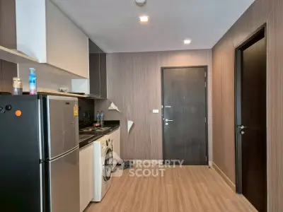 Modern kitchen with sleek appliances and wood paneling, featuring a washing machine and fridge.