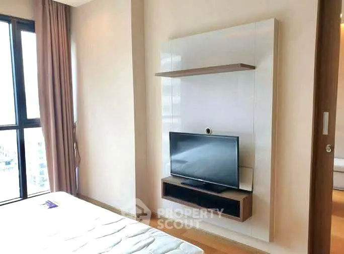 Modern bedroom with mounted TV and large window offering natural light.