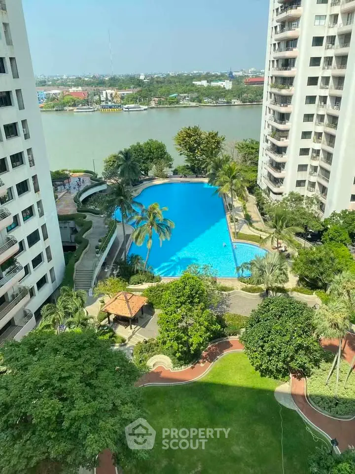 Stunning aerial view of luxury apartment complex with pool and lush gardens by the river.