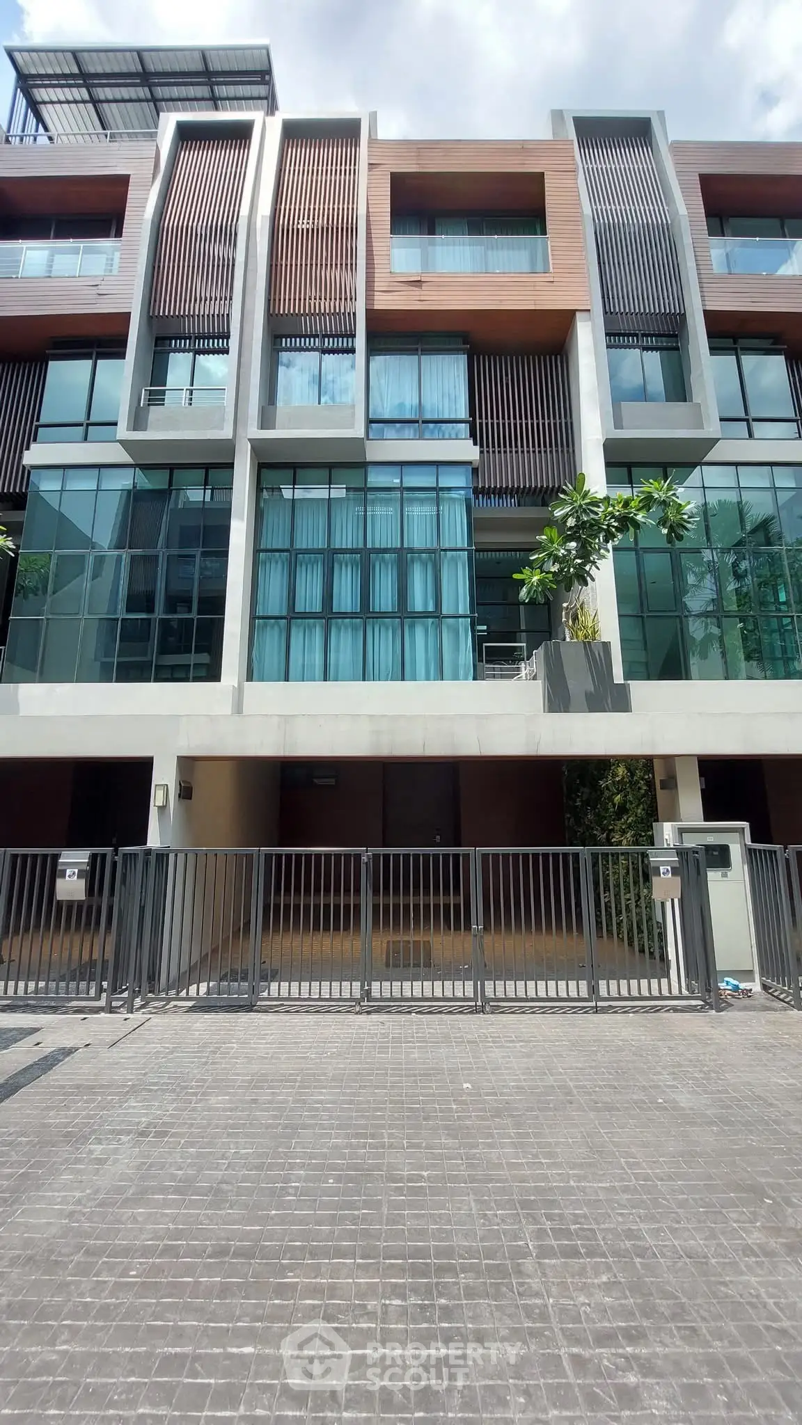 Modern multi-story building with glass facade and gated entrance