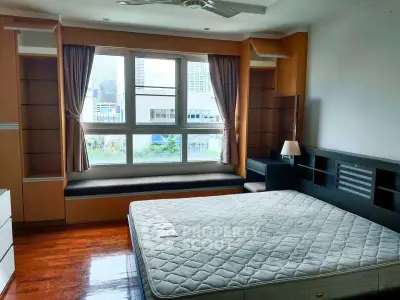 Spacious bedroom with large window and built-in shelves in modern apartment