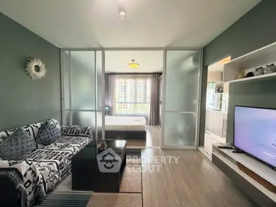 Modern living room with stylish decor and open view to bedroom, featuring sleek furniture and natural light.