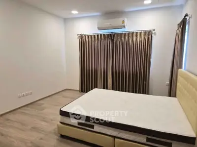 Spacious bedroom with modern air conditioning and elegant curtains, featuring a comfortable bed and stylish flooring.