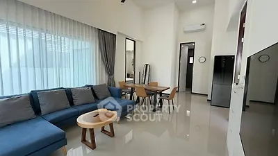 Modern living room with sleek furniture and open layout, featuring a stylish blue sofa and dining area.