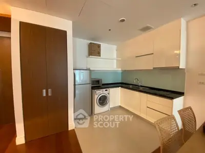 Modern kitchen with sleek cabinets, washing machine, and stainless steel fridge