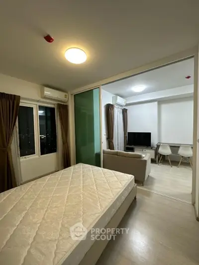 Modern apartment interior with bedroom and living area, featuring stylish furniture and large windows.