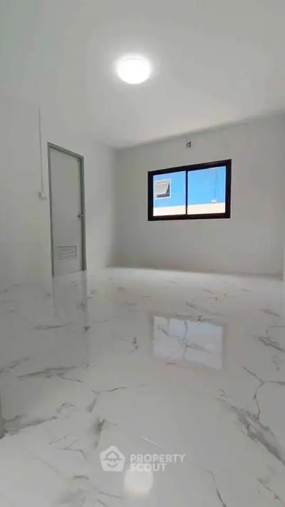 Spacious room with glossy marble flooring and large window offering natural light.
