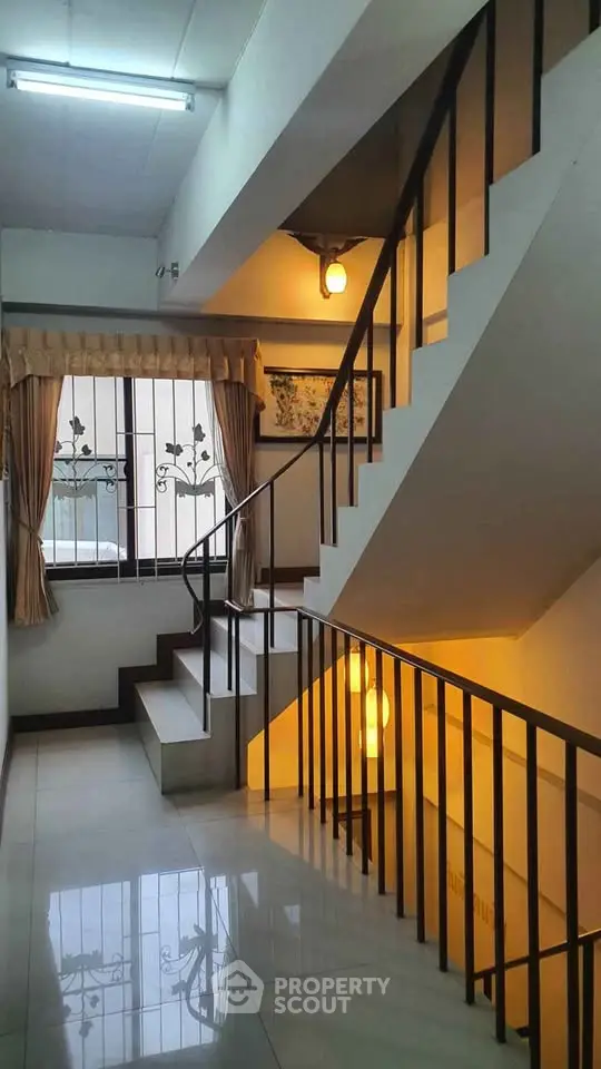 Elegant staircase with decorative window and warm lighting in a residential building.
