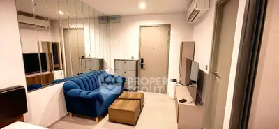 Modern living room with blue sofa, mirrored wall, and sleek TV setup