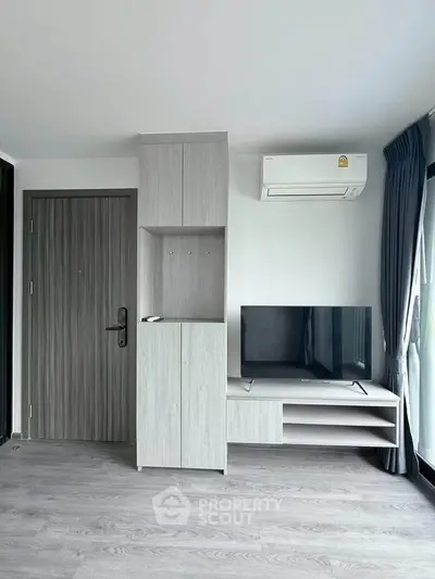 Modern living room with sleek furniture and air conditioning, featuring a stylish TV setup.