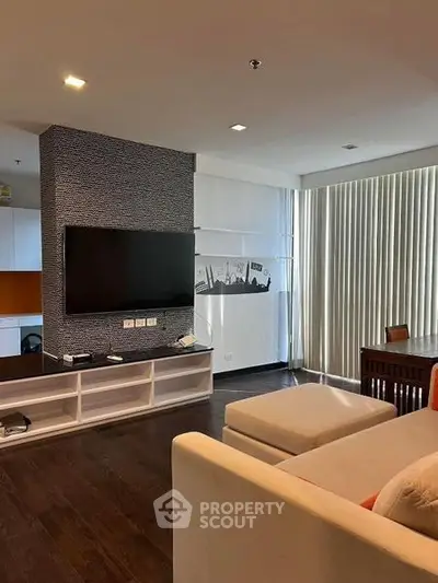 Modern living room with sleek TV setup and stylish decor, featuring floor-to-ceiling windows and cozy seating.