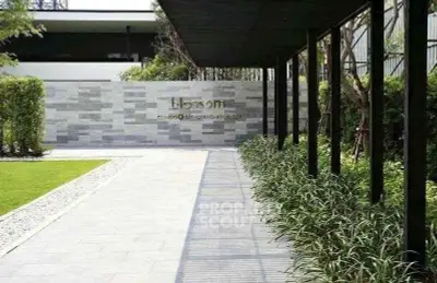 Modern building entrance with sleek design and lush greenery, perfect for urban living.