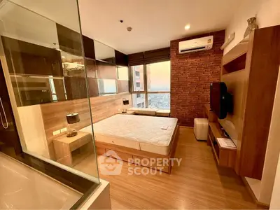 Modern bedroom with wooden flooring, large window view, and stylish brick accent wall.