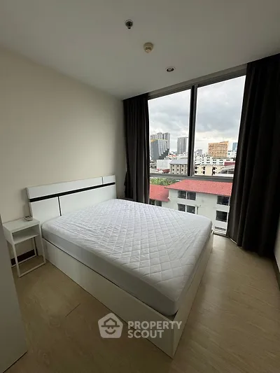 Modern bedroom with large window offering city views, featuring a minimalist design and ample natural light.
