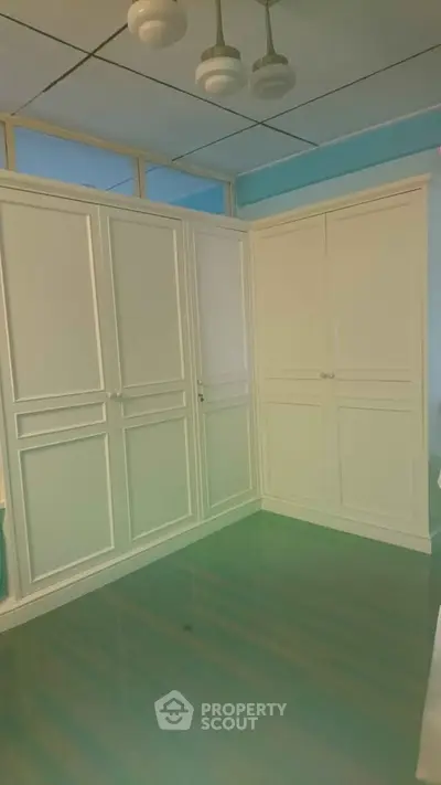 Spacious room with elegant white built-in wardrobes and glossy flooring.