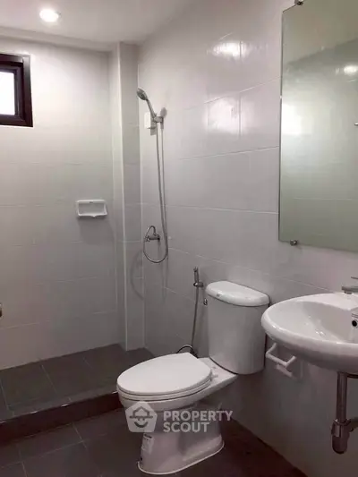Modern bathroom with sleek fixtures and tiled walls, featuring a shower and toilet.