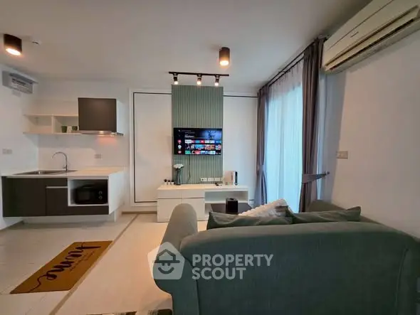 Modern living room with sleek kitchen, stylish sofa, and wall-mounted TV, perfect for contemporary urban living.