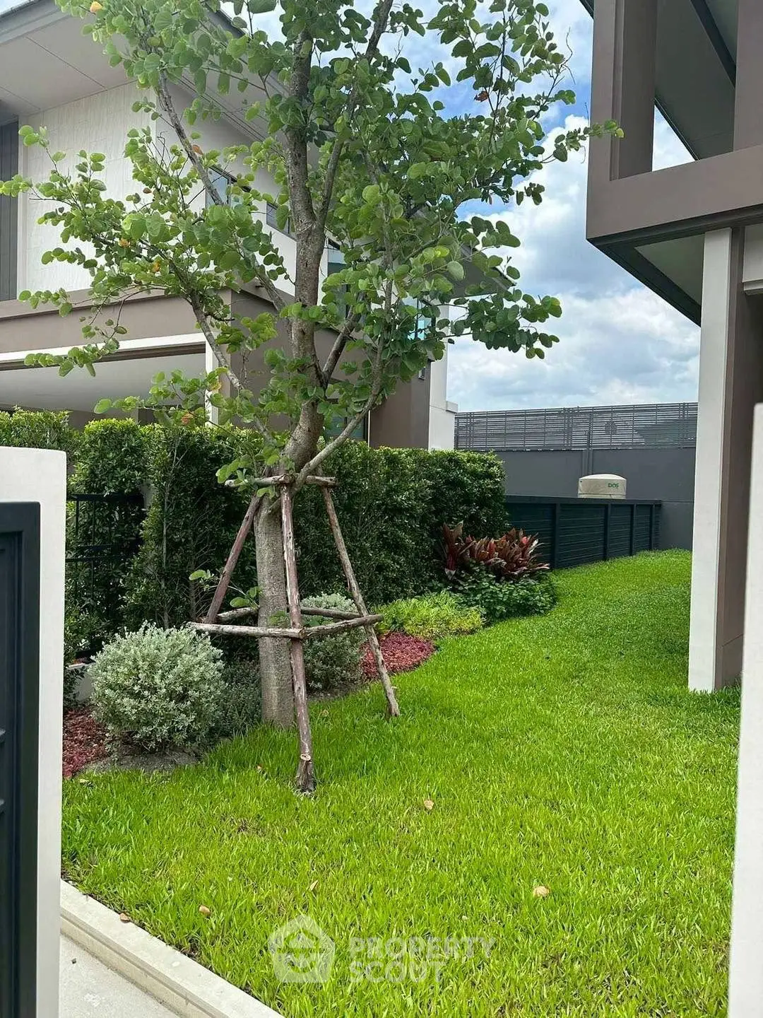 Modern residential building with lush green garden and contemporary architecture.