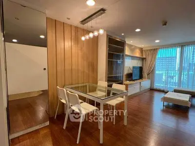 Modern living room with dining area and city view, featuring sleek furniture and warm lighting.